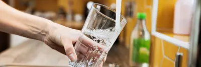 Hand holding glass under a tap with running water