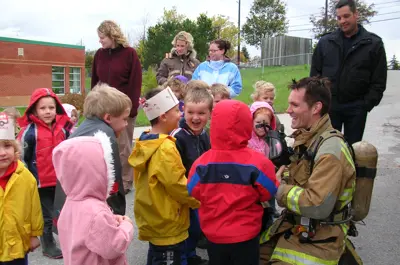 A firefighter smiles, talking with young students