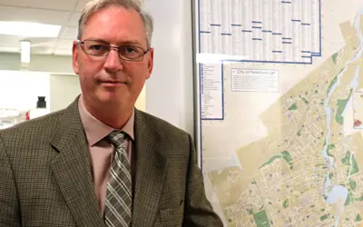 headhot style photo of Richard Freymond including City of Peterborough Map beside him.