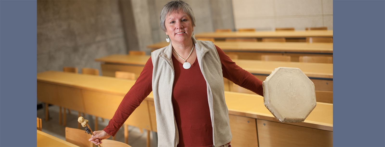 A person standing, holding a drum in one hand