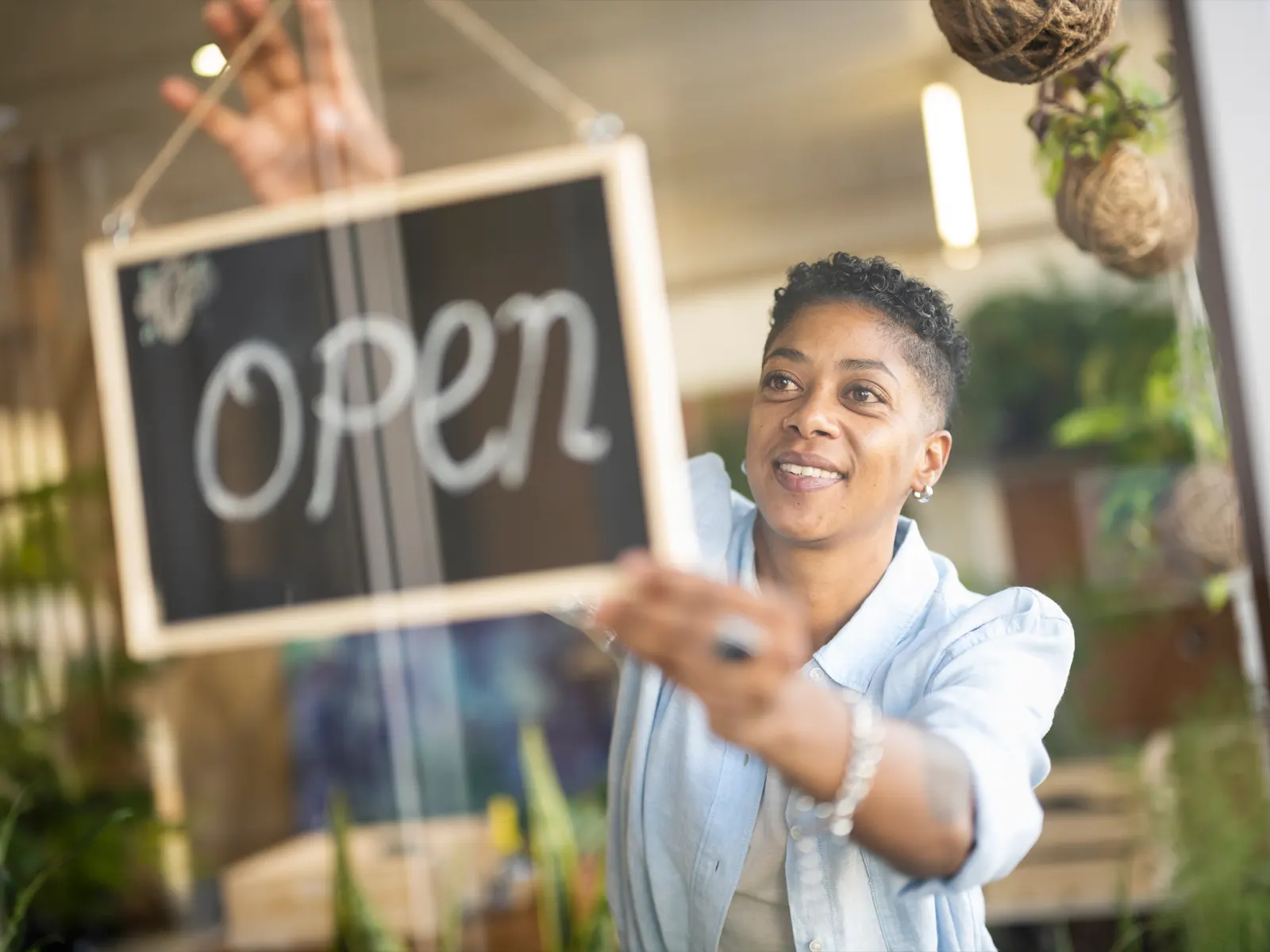 person hanging an open sign in the window