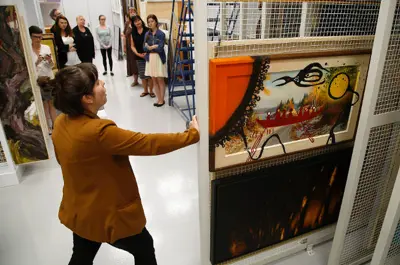 Person pulling painting from storage holder