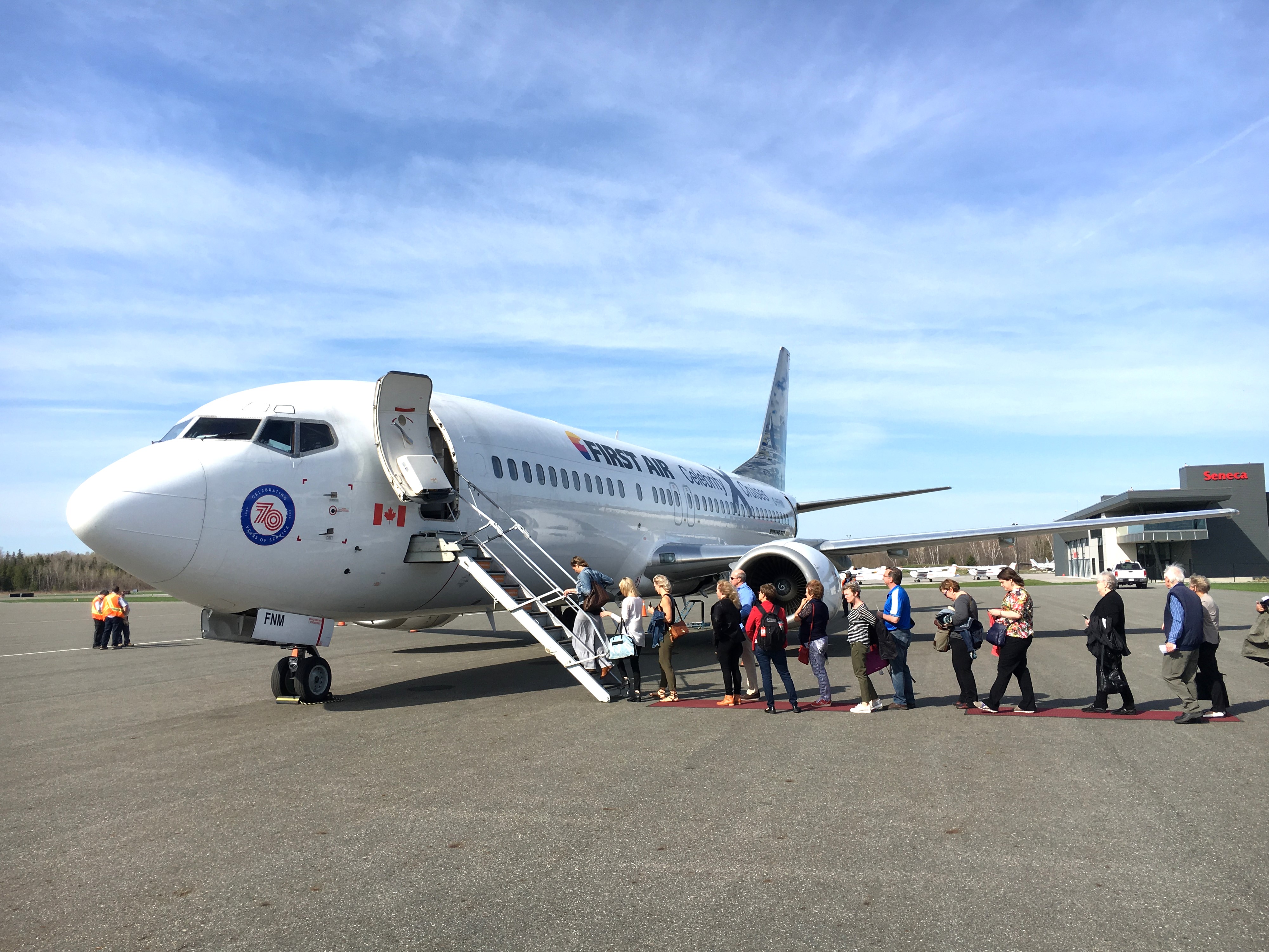 People lined up outside of a plane, climbing stairs to board the plane