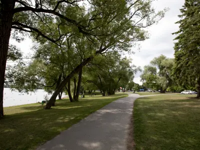 A gravel trail with green grass and trees around it going into the distance.