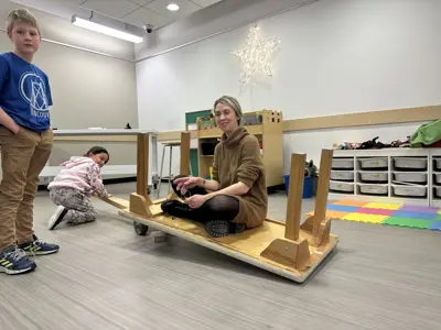 Person sitting on a platform with two young people interacting