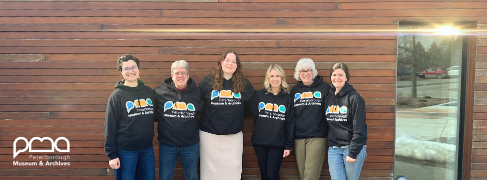 Staff stand together outside the Museum wearing hoodies with the new logo