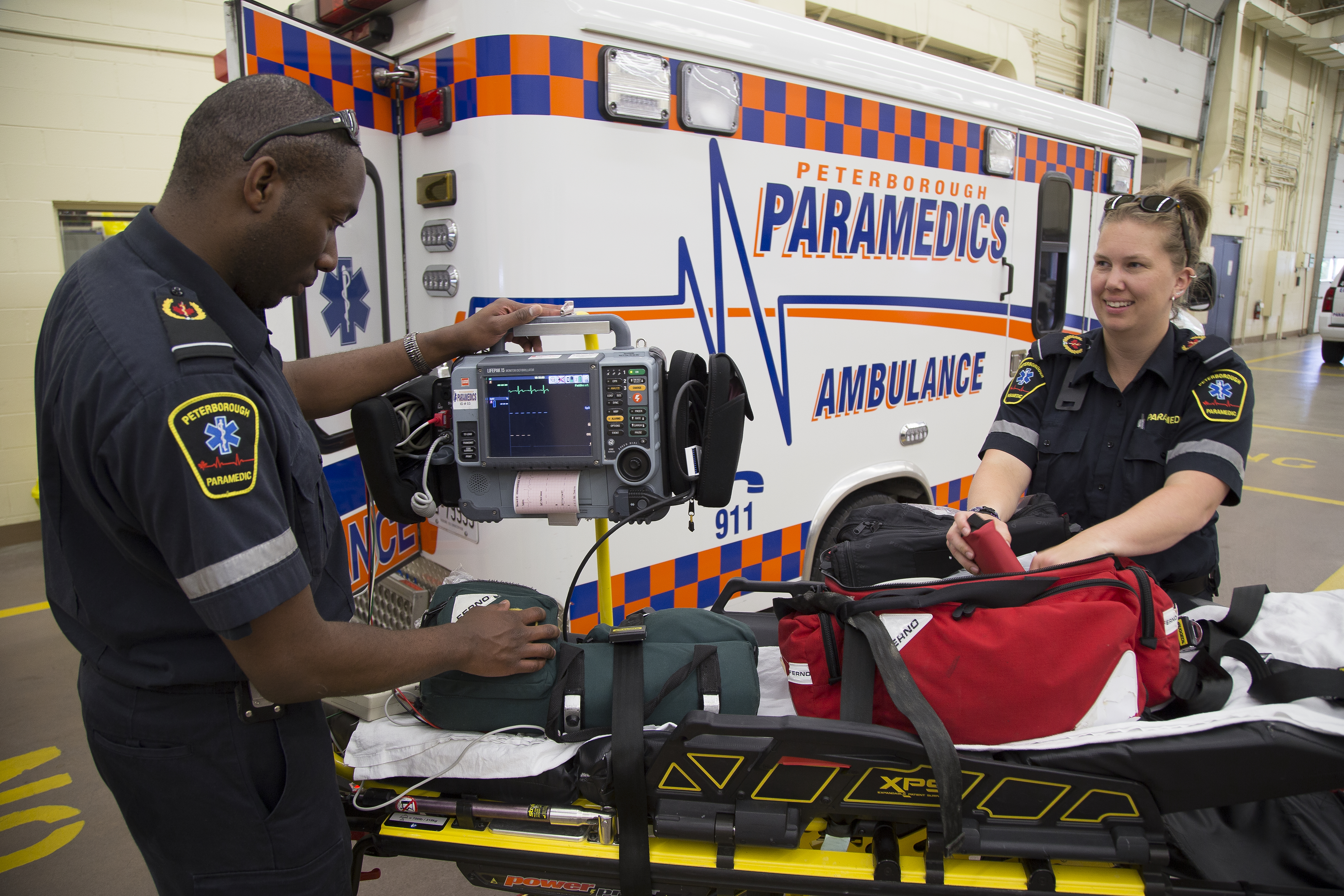 Two paramedics standing next to an ambulance