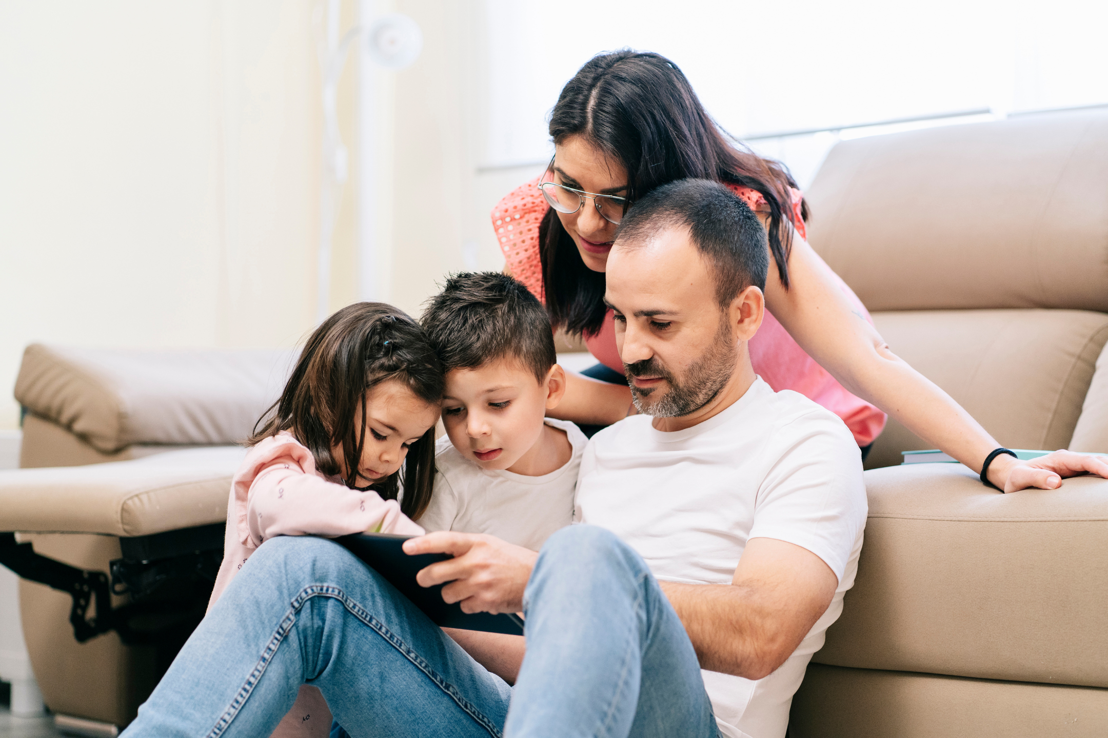 Two adults with two children looking at a tablet
