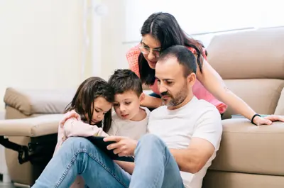 Two adults with two children looking at a tablet