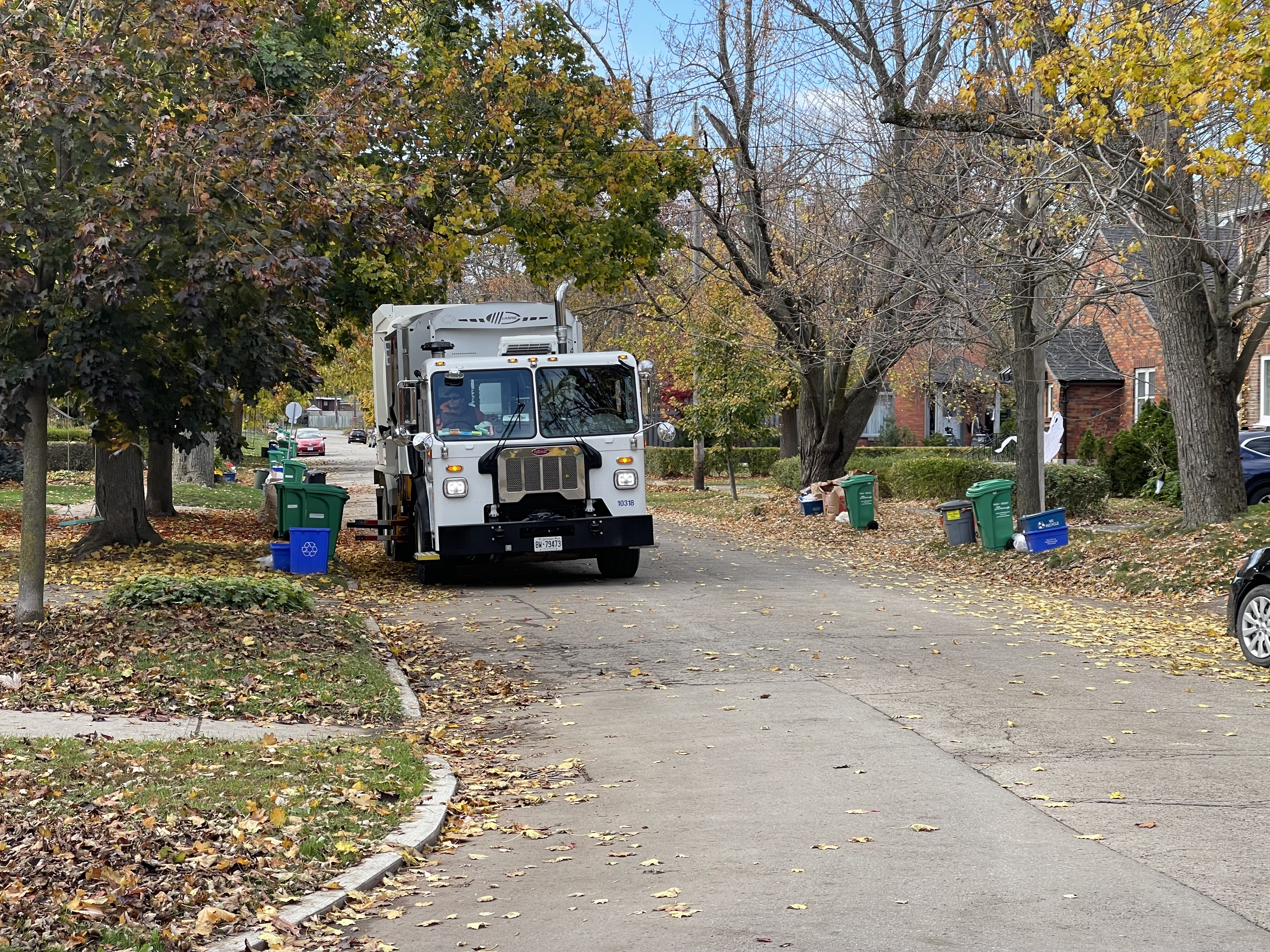 Green bin and garbage collection truck on a residentials street