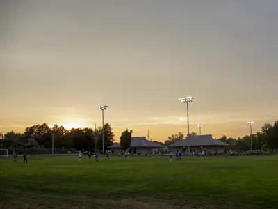 A soccer game at Eastgate Park while the sun is setting